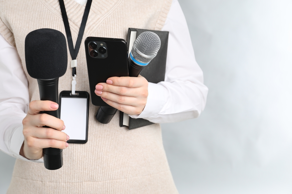 Journalist,With,Microphones,,Smartphone,And,Notebook,On,Grey,Background,,Closeup.